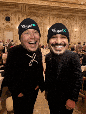 two men wearing beanies that say blizzard are laughing