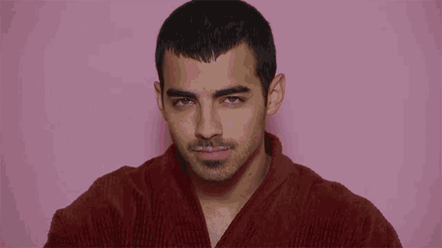 a man wearing a red robe is looking at the camera