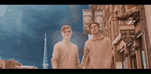 two men walking down a street with a sign that says buy one fair get two fair free