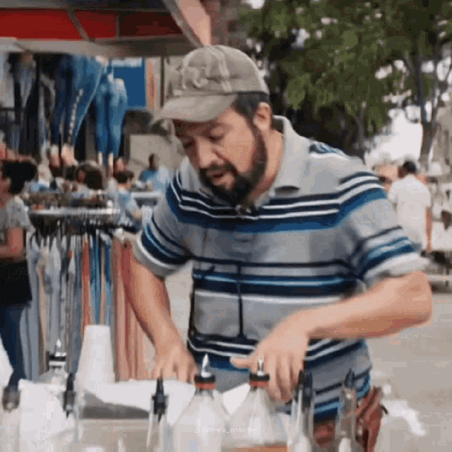 a man with a beard wearing a hat and a striped shirt is making a drink