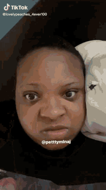 a woman is making a funny face while laying in bed with a stuffed animal