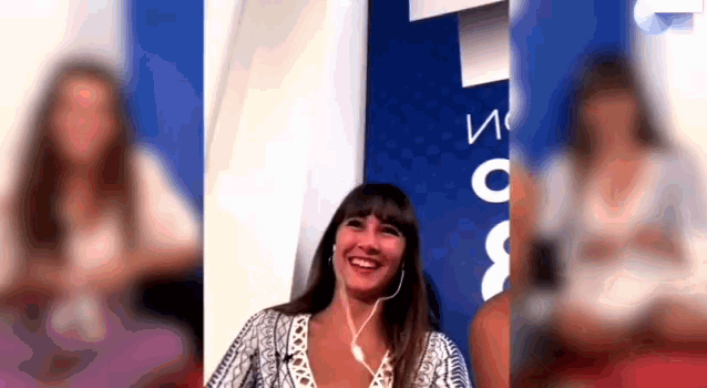 a woman wearing headphones is smiling in front of a sign that says ' io ' on it