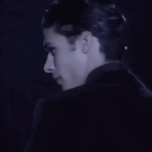 a man in a suit and tie is standing in a dark room .
