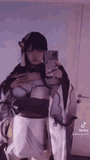 a woman is taking a selfie in front of a mirror while wearing a cosplay costume .