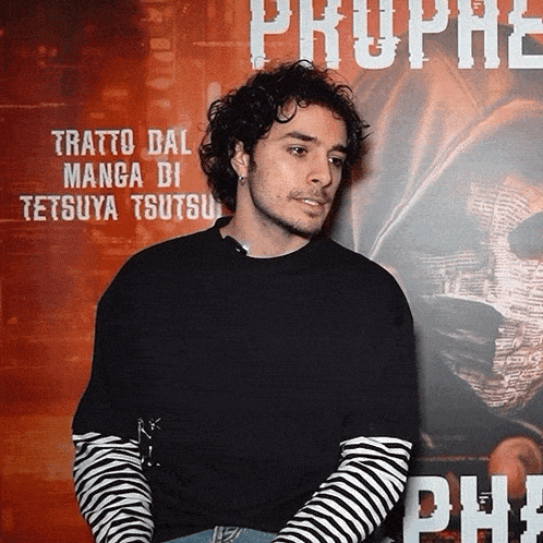 a man stands in front of a poster that says prophe