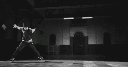 a black and white photo of a man and a woman dancing in a dark room .