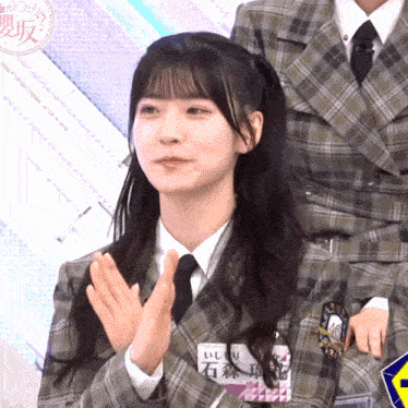 a girl wearing a plaid jacket and tie has a name tag that says 10 on it