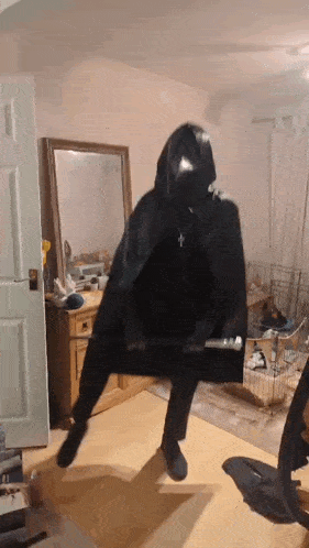 a person in a black cape holding a bat in a room