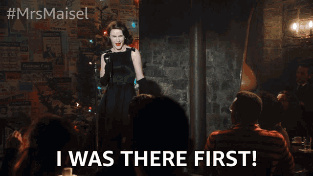 a woman singing into a microphone with the words " i was there first " below her