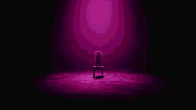 a person is sitting in a chair in a dark room with purple lights .