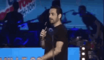 a man is holding a microphone on a stage in front of a sign that says 106-10h