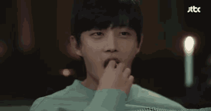 a close up of a young man 's face in a dark room with a candle in the background .