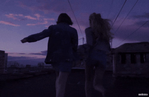 two women holding hands in front of a purple sky with the name melsica on the bottom right