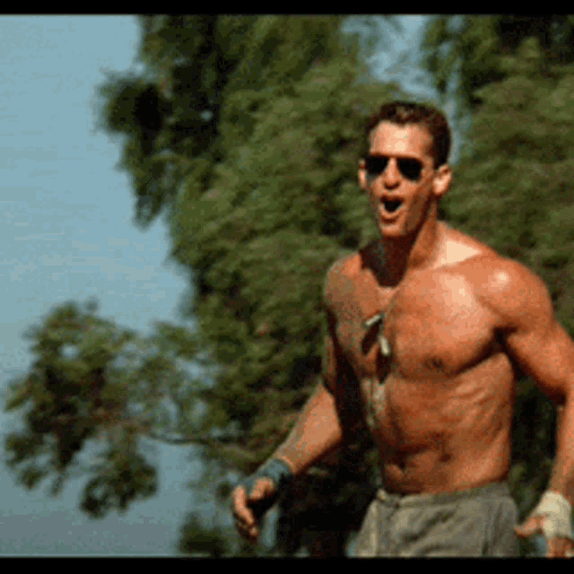a shirtless man wearing sunglasses and a dog tag on his chest
