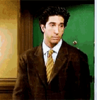 a man wearing a suit and tie is standing in front of a green door .