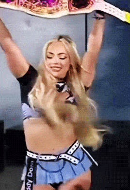 a woman in a blue skirt is holding a belt that says " daddy dom " on it