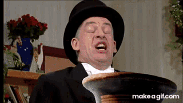 a man in a top hat and bow tie is holding a bowl with his mouth open .