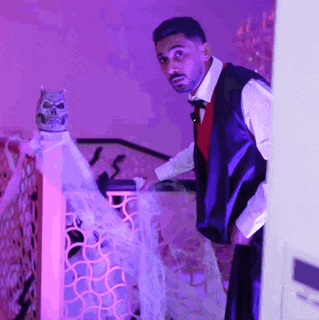 a man in a tuxedo stands in front of a purple light