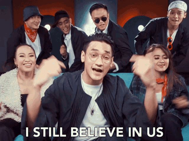 a group of people are sitting on a blue couch and one of them is saying i still believe in us
