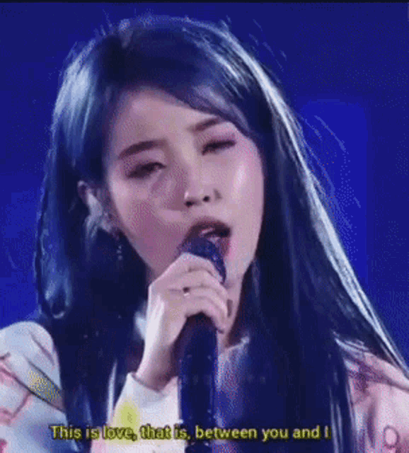 a woman singing into a microphone with the words " this is love that is between you and i " on the bottom