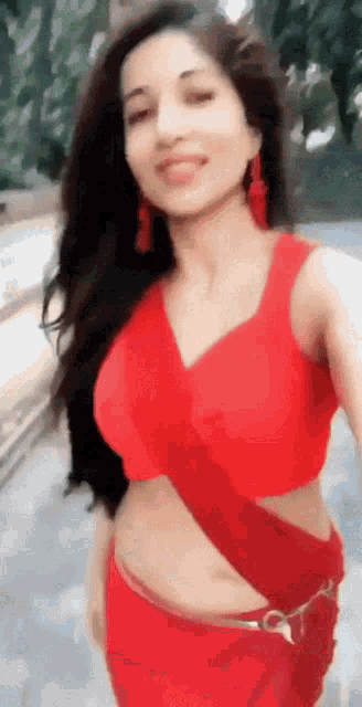 a woman in a red crop top and red pants is taking a selfie