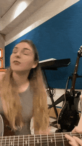 a woman singing while playing a guitar in front of a keyboard