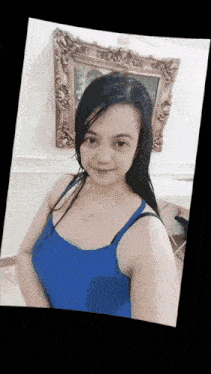 a woman in a blue tank top stands in front of a painting