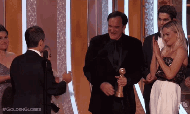 a group of people on a stage with #goldenglobes written on the bottom right