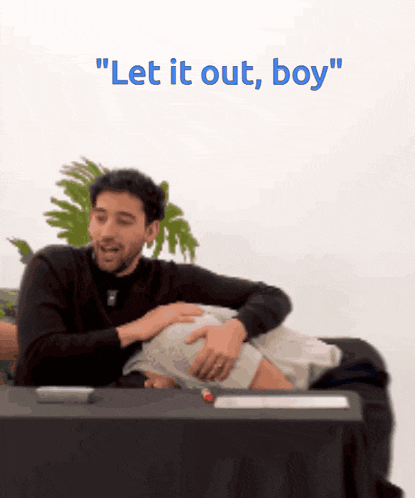 a man is putting his hand on another man 's stomach and the words " let it out boy " are above him