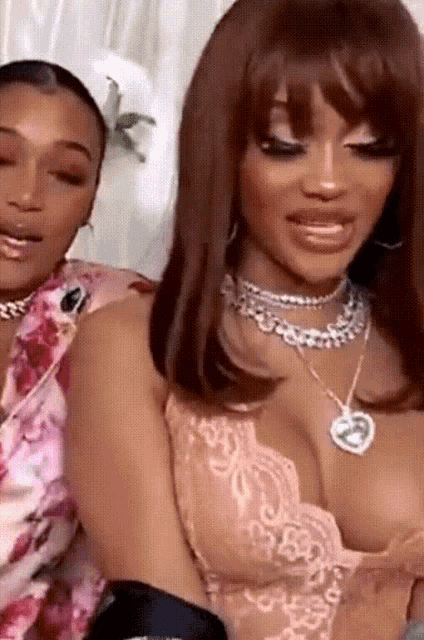 two women are sitting next to each other and one of them is wearing a necklace with a heart on it