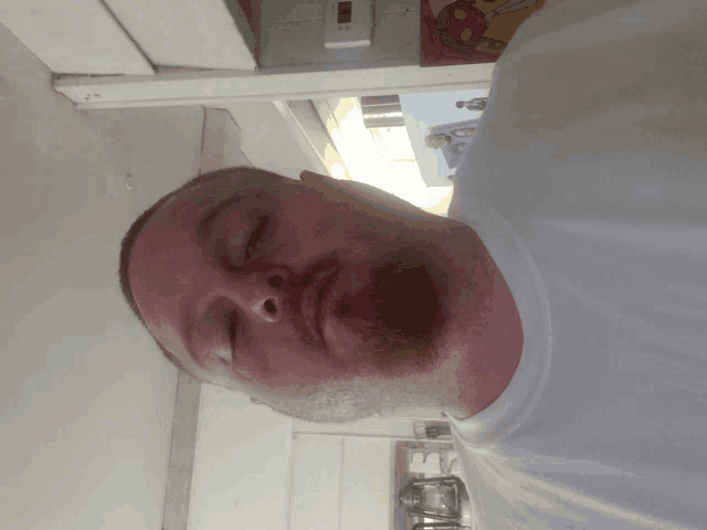 a man with his eyes closed is wearing a white shirt and has a beard
