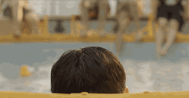 a man is swimming in a pool with a yellow float