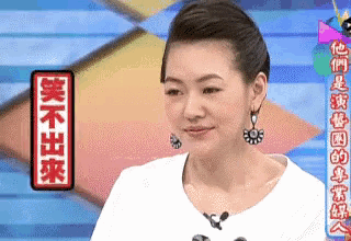 a woman wearing a white shirt and earrings is standing in front of a sign that says ' chinese ' on it .