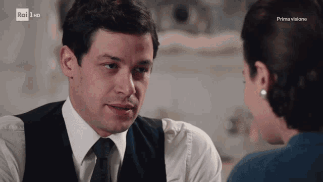a man in a suit and tie looks at a woman in a blue shirt