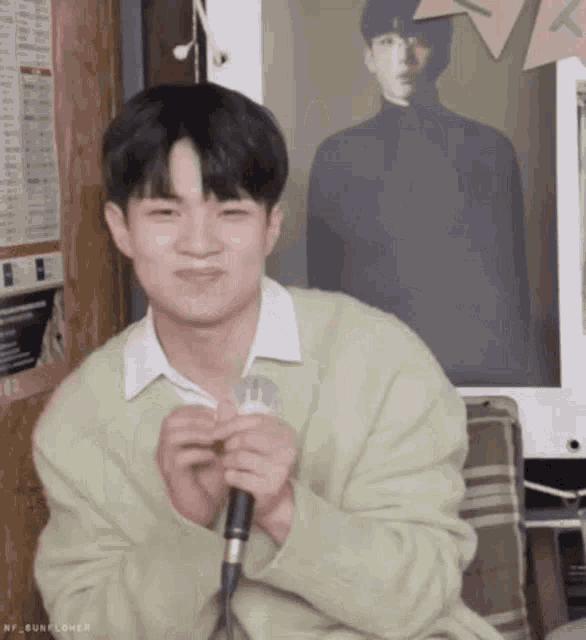 a young man is sitting in front of a microphone .