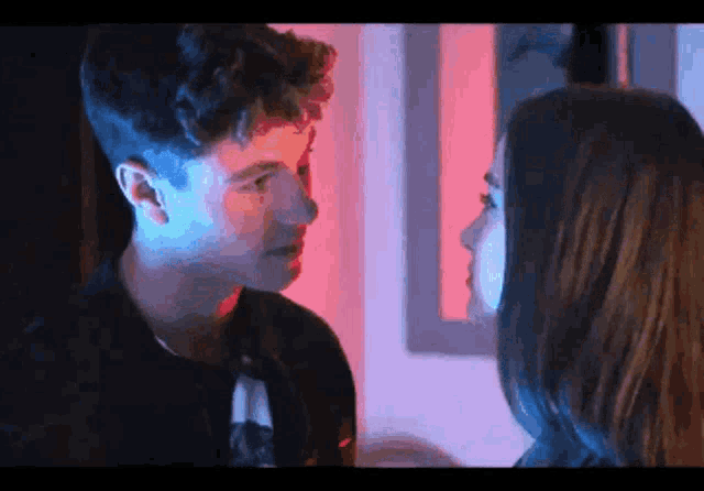 a man and a woman are looking into each other 's eyes in a dark room .