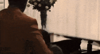 a man in a suit is playing a piano in a living room .