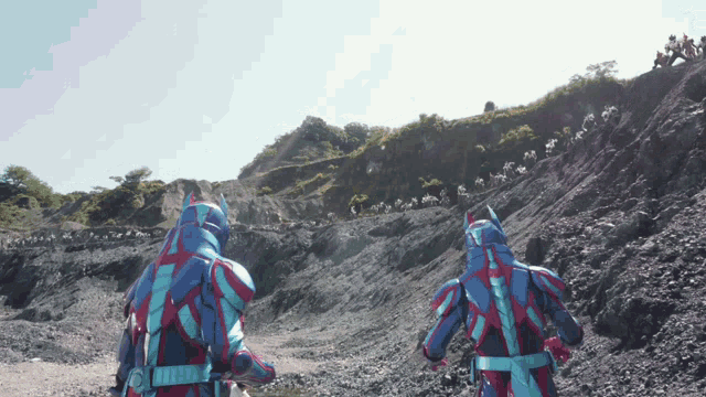 a man in a blue and red suit is walking down a rocky hillside