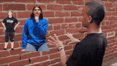 a man wearing a black shirt that says genesis talks to another man