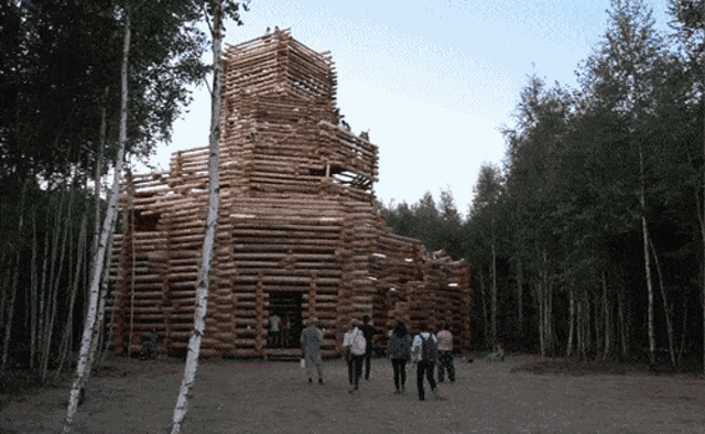 a group of people are standing in front of a large wooden structure