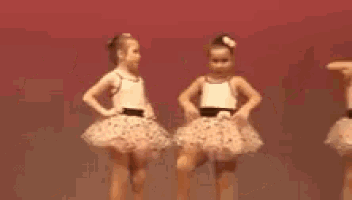 two little girls are standing next to each other on a stage .