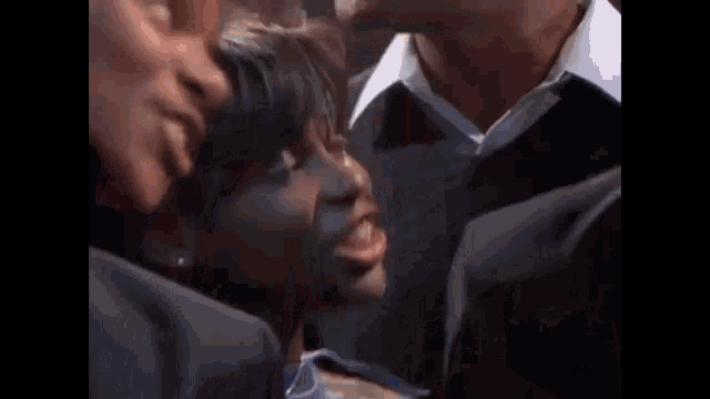 a group of people are laughing and singing together in a crowd .