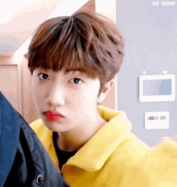 a young boy wearing a yellow jacket and red lipstick