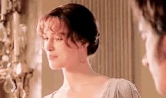 a woman is standing next to a man in a room looking at him .