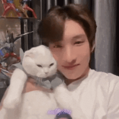 a man is holding a white cat in his arms and smiling .