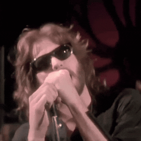 a man singing into a microphone with sunglasses on