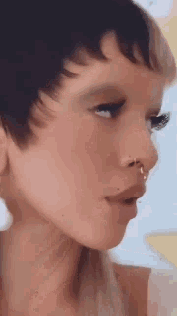 a close up of a woman 's face with a nose ring and earrings .