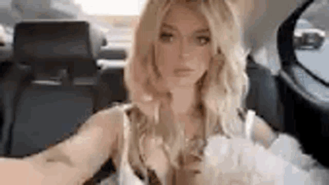 a woman is taking a selfie in the back of a car .