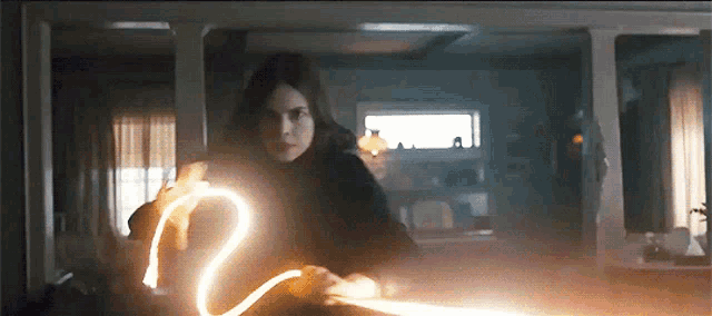 a woman in a dark room is holding a light that looks like a heart ..