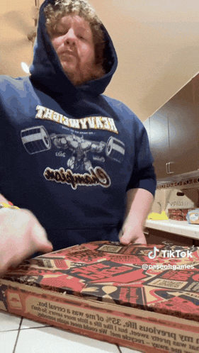 a man wearing a hoodie that says ' the way i am ' on it is opening a pizza box